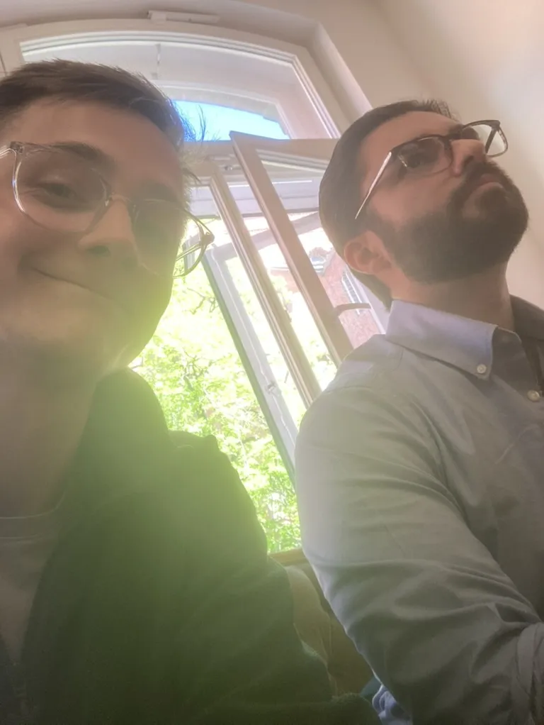 Zwei Teammitglieder machen ein Selfie am offenen Fenster